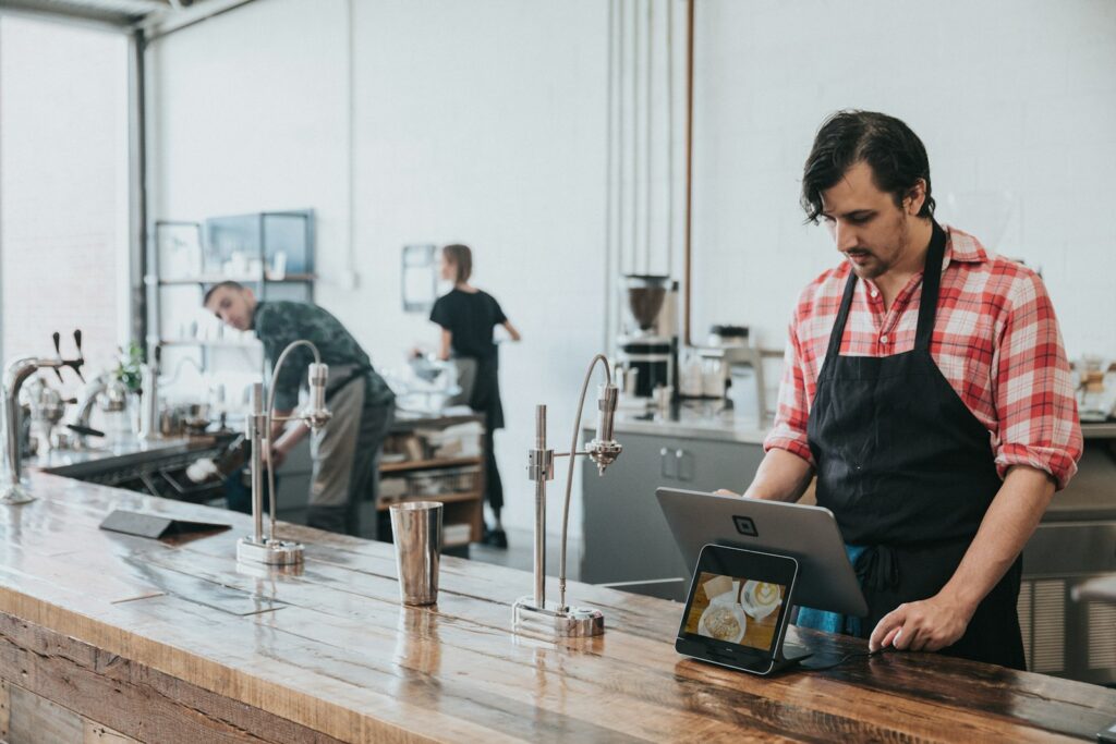 A barista using a tablet at a wooden counter
